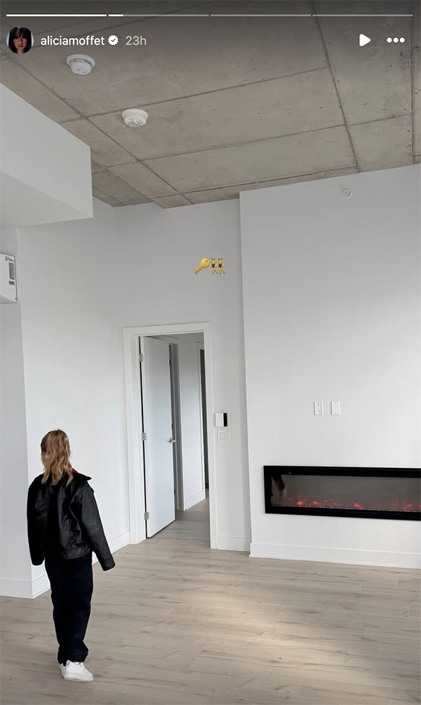 La fille d'Alicia Moffet explore un espace vide avec plafond en b&eacute;ton, plancher de bois et foyer &eacute;lectrique encastr&eacute;