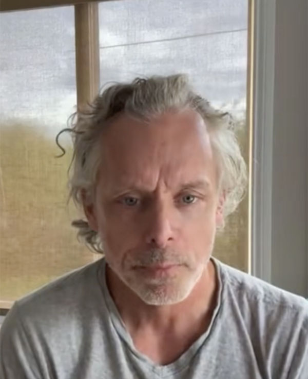 François Lambert regardant la caméra d'un air sérieux, assis près d'une fenêtre