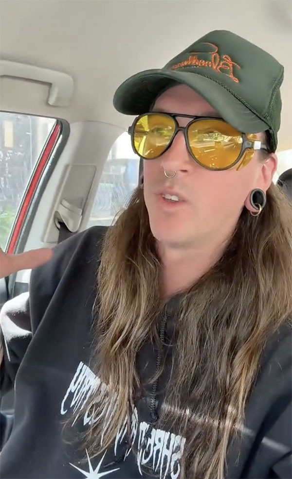 @acidblais aux longs cheveux bruns, lunettes de soleil jaunes et casquette verte, assise dans une voiture et parlant &agrave; la cam&eacute;ra
